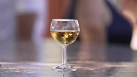 close up of glass of white wine on a table during an outdoor gathering