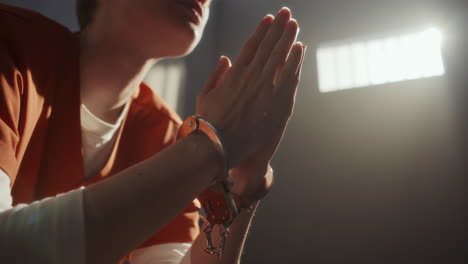 close-up of handcuffed inmate clasping hands in prayer