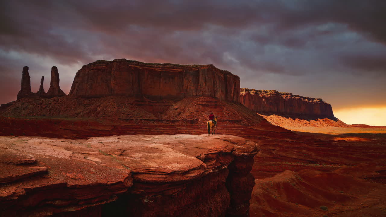 cinemagraph - lapso de tiempo de bucle de video continuo de un nativo americano navajo en un caballo mirando las famosas formaciones rocosas en el monumento del valle del monumento en utah - arizona, américa - ee.uu. al atardecer