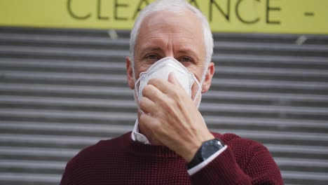 caucasian man out and about in the street wearing on a face mask against coronavirus