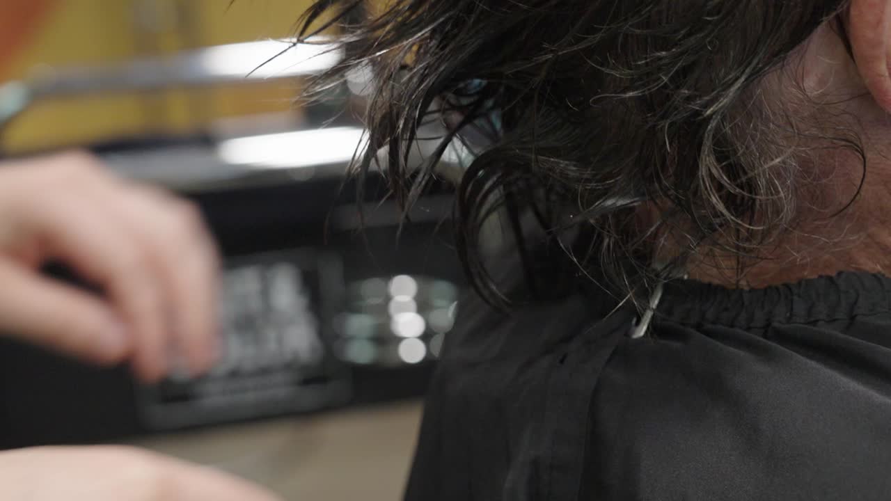 A hairstylist dries a man's hair with a towel at a salon