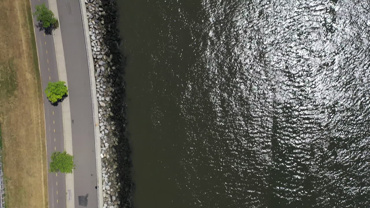 브루클린의 쇼어 파크웨이 근처에 있는 낮은 뉴욕 만의 돌로 된 해안을 내려다보는 하향식 전망