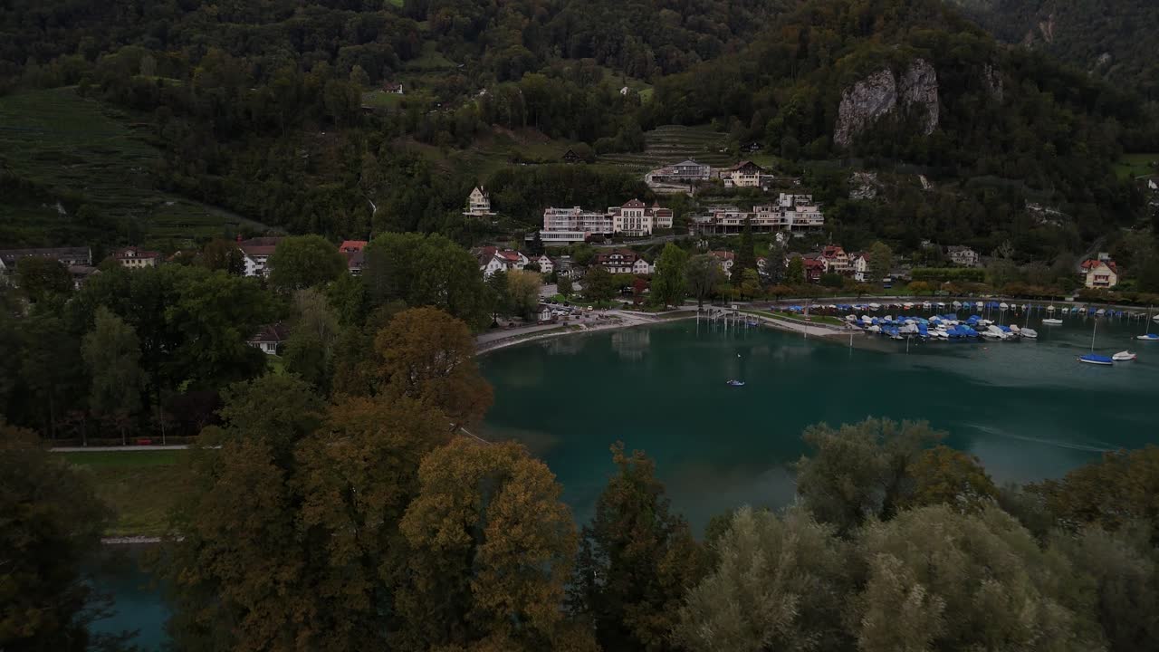 Aerial view of a residential coastal area along the banks of Lake Walensee in Switzerland, showcasing charming homes nestled against the serene waters and surrounded by lush greenery