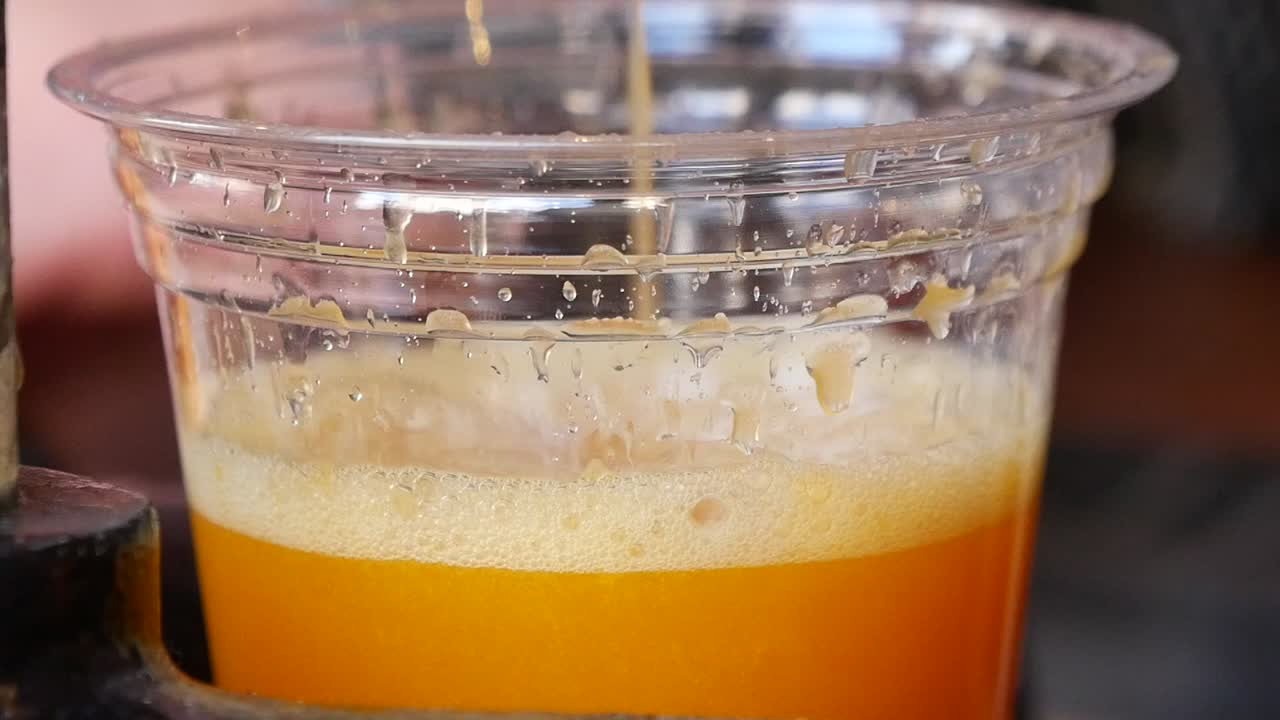 Succo d'arancia fresco versato in un bicchiere di plastica