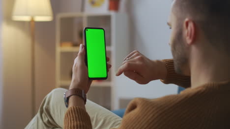 man is shopping online ordering in app in smartphone swiping and tapping by finger green screen on gadget modern technology and service