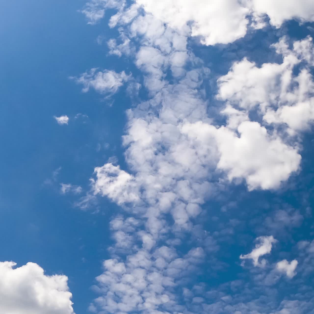 Light airy soft clouds in the beautiful azure sky. Cloudscape moved by the wind in the atmosphere. Low angle view timelapse