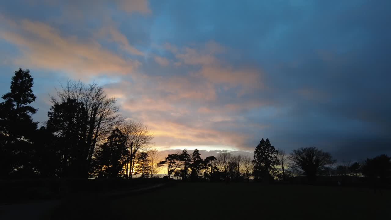 Fast moving clouds time lapse at a beautiful sunset with silhouette of trees