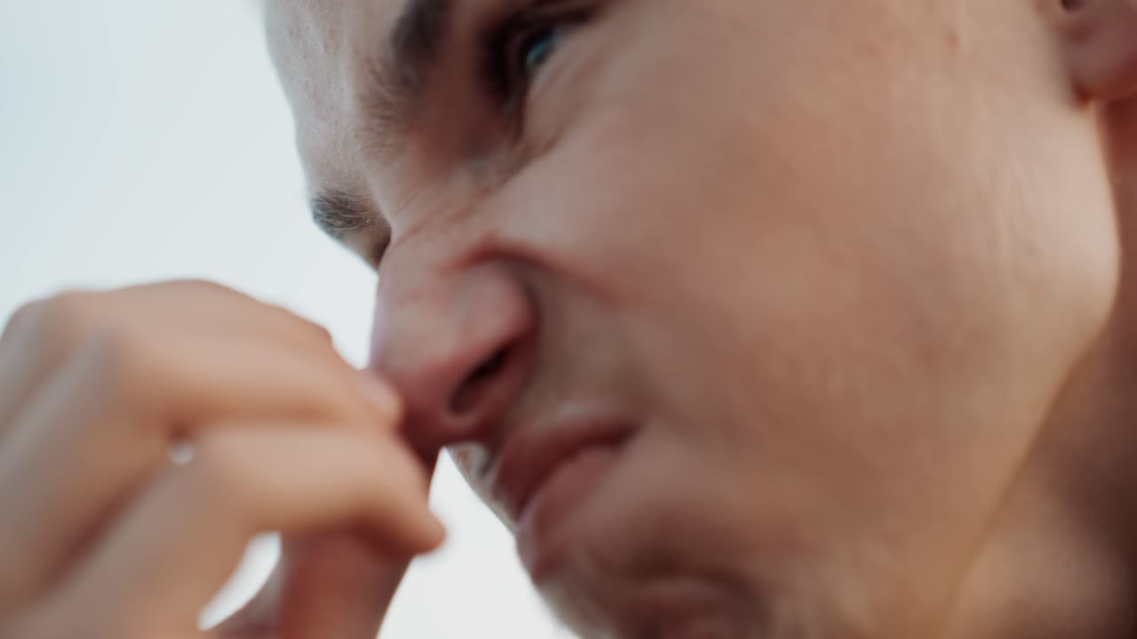 Unzufriedener Mann reagiert schlecht auf einen üblen Geruch. Eine Person zeigt Ekel, nachdem sie ein unangenehmes Aroma im Freien wahrgenommen hat. Ein junger Beobachter verzieht das Gesicht, als er einen beleidigenden und unerwünschten Geruch im Freien wahrnimmt.