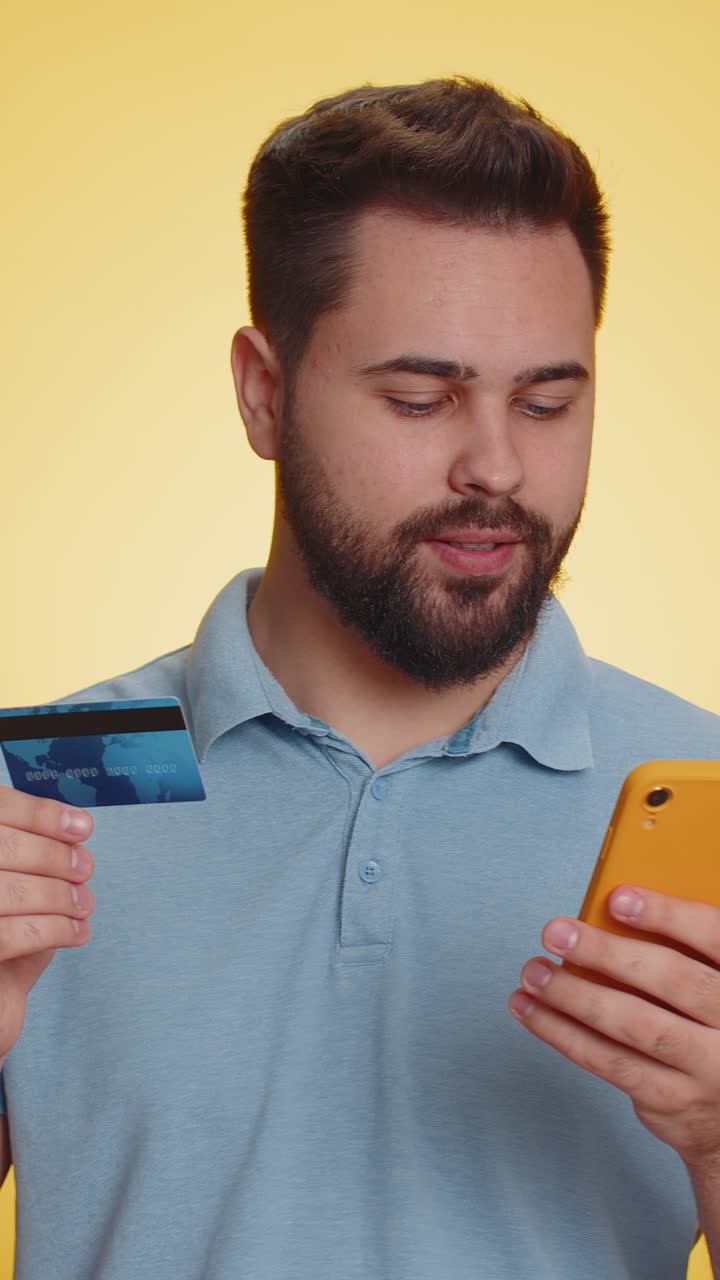 Uomo felice che usa la carta di credito e lo smartphone mentre trasferisce denaro acquista online