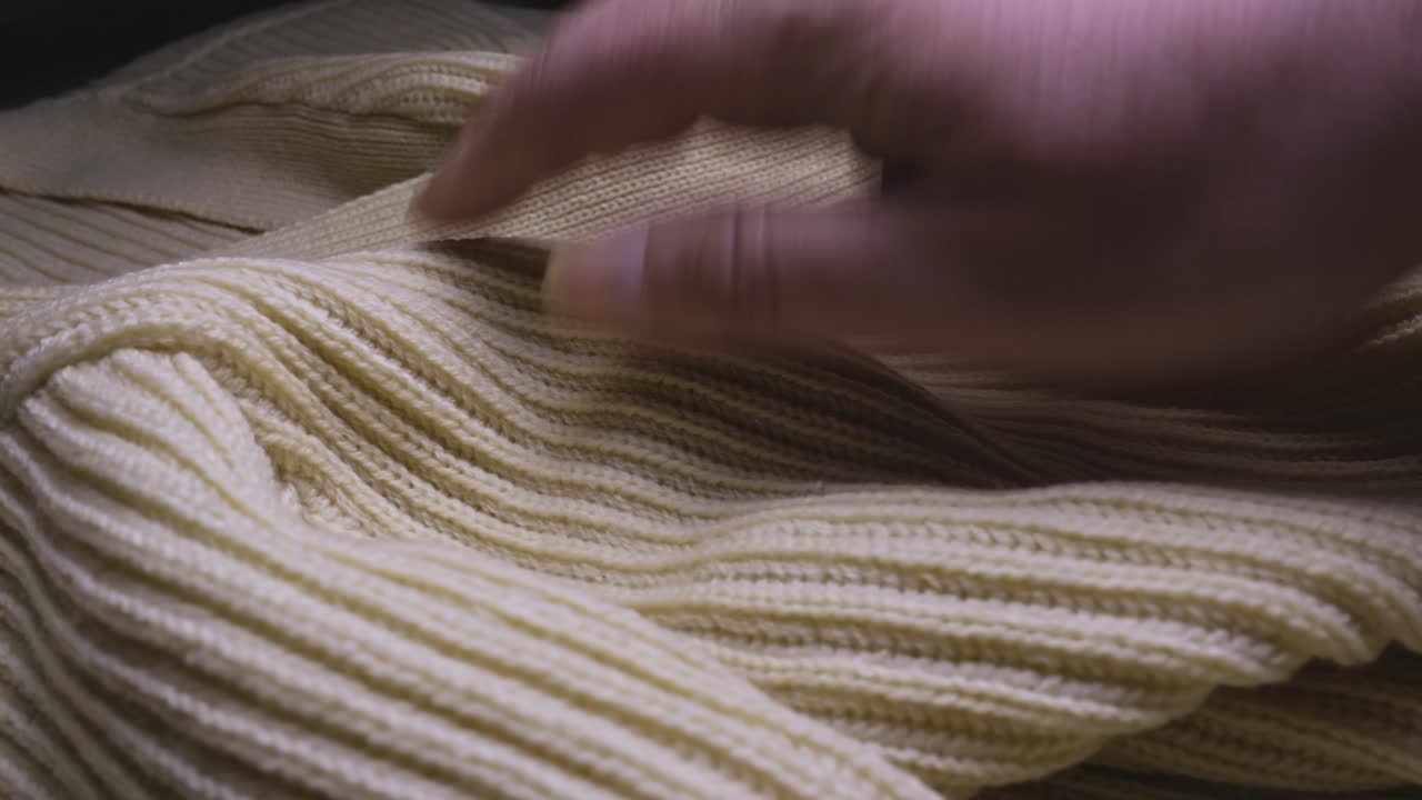 Hand feeling the texture and ribbed pattern of a knitted Wool jumper
