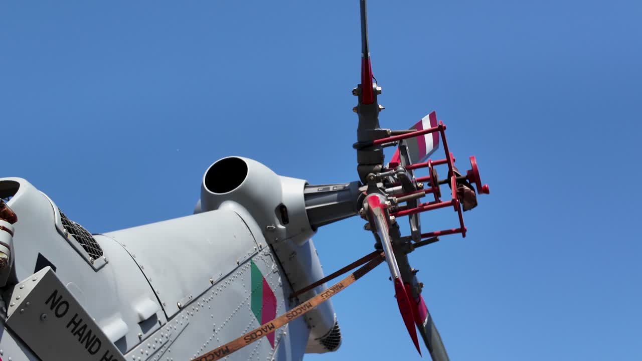 Close up of a military helicopter's tail rotor, featuring warning signs for safety