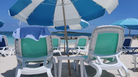 relax in caribbean style: empty beach chairs and umbrellas adorn the sandy shores against the backdrop of azure waters and skies, epitomizing tropical tranquility