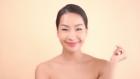 happy satisfied asian woman after cosmetic skincare and spa treatment touching her face, close up slowmotion