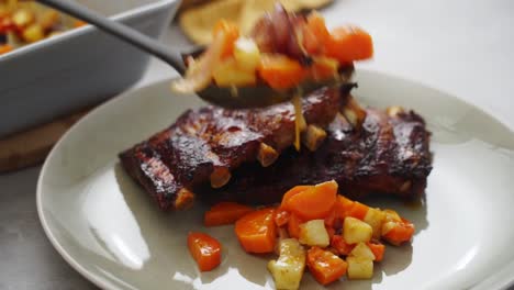 Crop-person-serving-ribs-with-vegetables