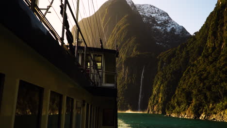 Milford-Mariner-vessel-and-Stirling-falls-during-golden-sunset,-handheld-view