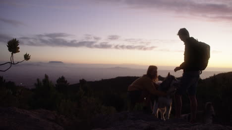 a-couple-hiking-with-their-dog-at-sunset