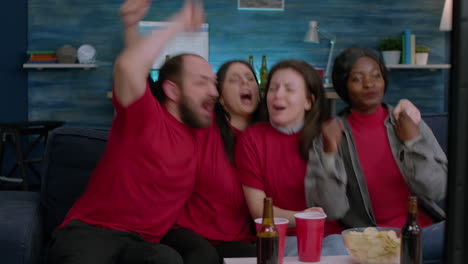 Excited-mixed-race-friends-watching-sport-on-television-celebrating-football-goal