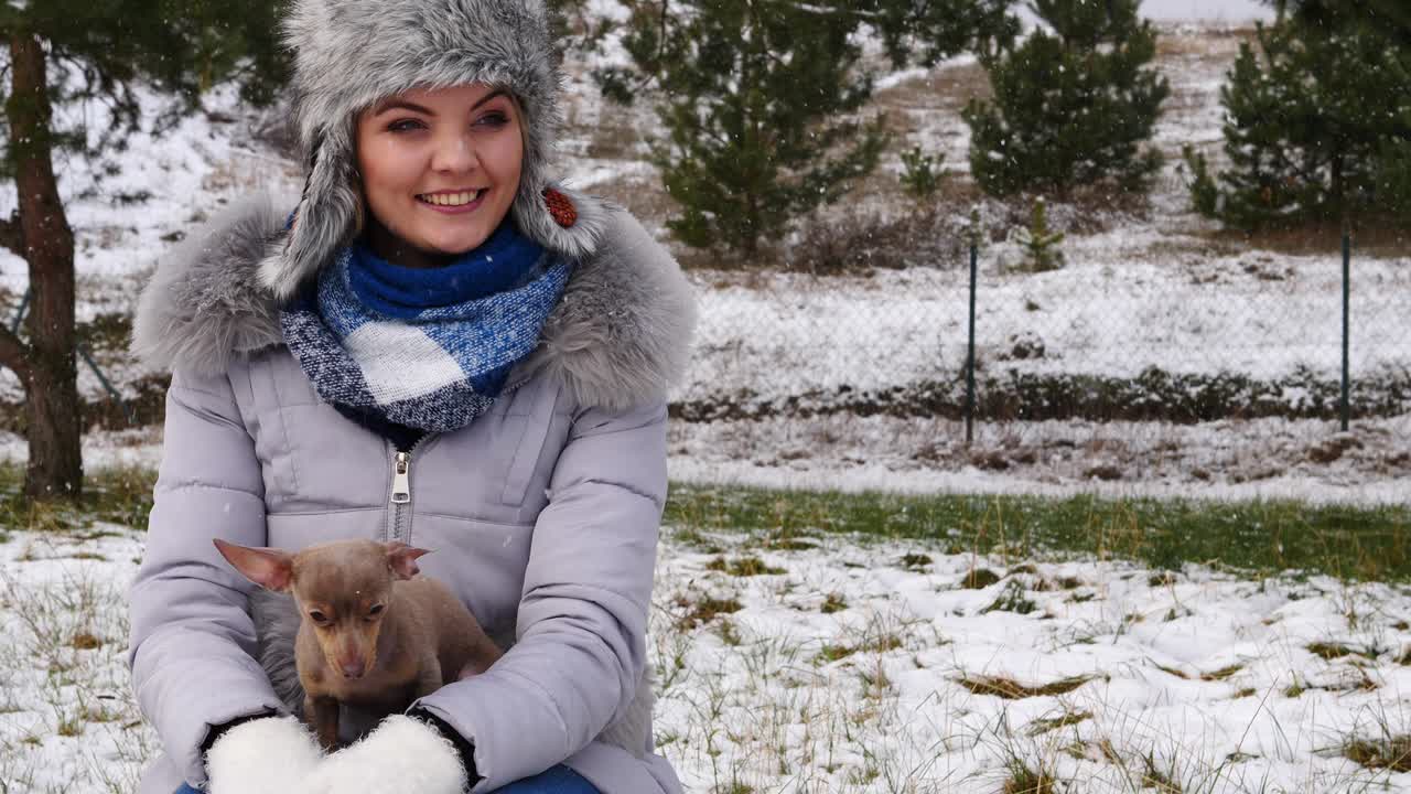 mujer jugando con su pequeño perro fuera del invierno