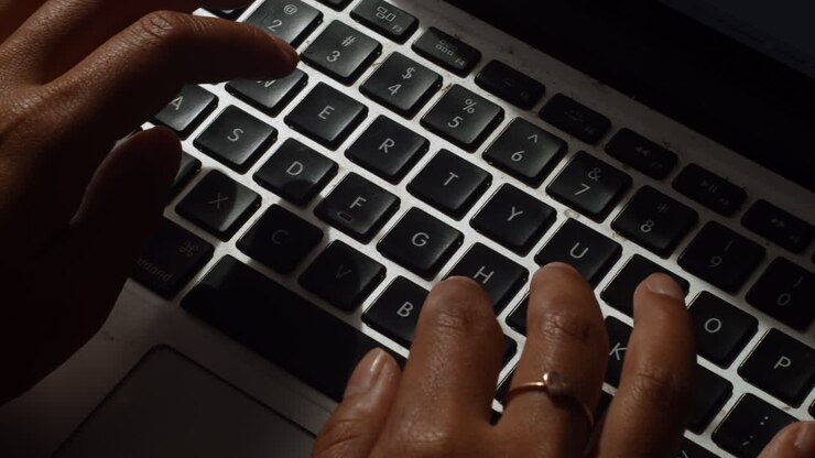 Eine Nahaufnahme einer Frau, die an ihrem Laptop tippt, während sie von zu Hause aus arbeitet
