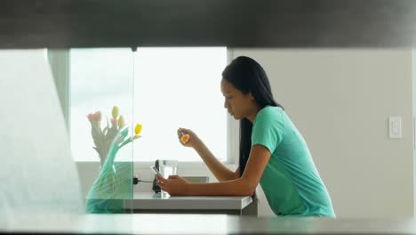 Woman-using-mobile-phone-while-having-breakfast-in-kitchen-4k