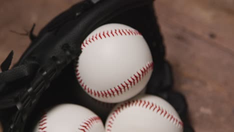 Nahaufnahme-Eines-Baseball-Stilllebens-Im-Studio-Mit-Bällen-Im-Fängerhandschuh-Auf-Holzboden-1