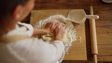 woman kneading dough on a wooden board in the kitchen