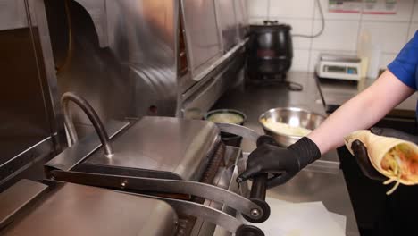 preparing a wrap on a grill in a restaurant kitchen