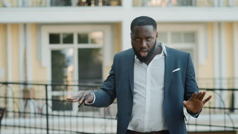 Smiling-afro-businessman-dancing-on-urban-street