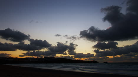 Hermosa-Puesta-De-Sol-Escénica-Hasta-El-Anochecer-Lapso-De-Tiempo-A-Lo-Largo-De-La-Costa-De-La-Playa-Fistral-De-Newquay-Con-Nubes-En-Movimiento-Rápido-En-El-Cielo-En-Cornualles,-Inglaterra,-Reino-Unido