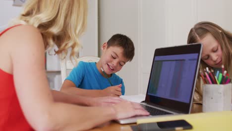 Kaukasische-Mutter-Hilft-Ihrem-Sohn-Bei-Den-Hausaufgaben,-Während-Sie-Zu-Hause-Einen-Laptop-Benutzt