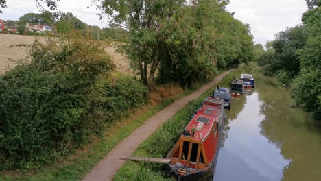 botes de canal amarrados en la orilla tomando un descanso de conducir lentamente por el canal, tiro de trípode desde un puente en el canal de kennet y avon en inglaterra a última hora de la tarde