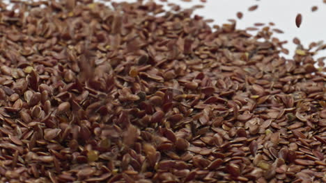 heap flax seeds falling on creamy surface dairy dessert close up. healthy food.