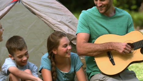 padre tocando la guitarra para su familia