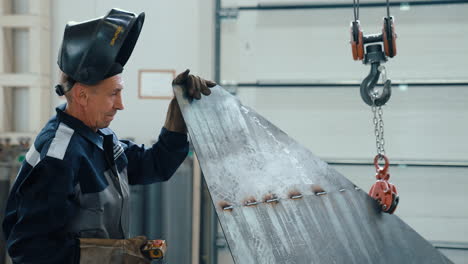 vinnytsia, ukraine - january 19, 2023: a welder worker in gray overalls lifts a metal product using a crane