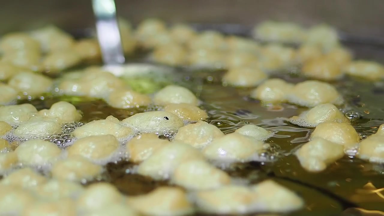 Piccole palline di pasta che friggono in olio caldo