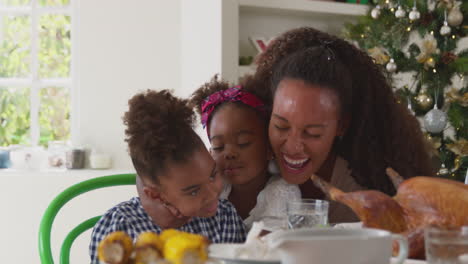 mother with two children celebrating family christmas at home eating meal together