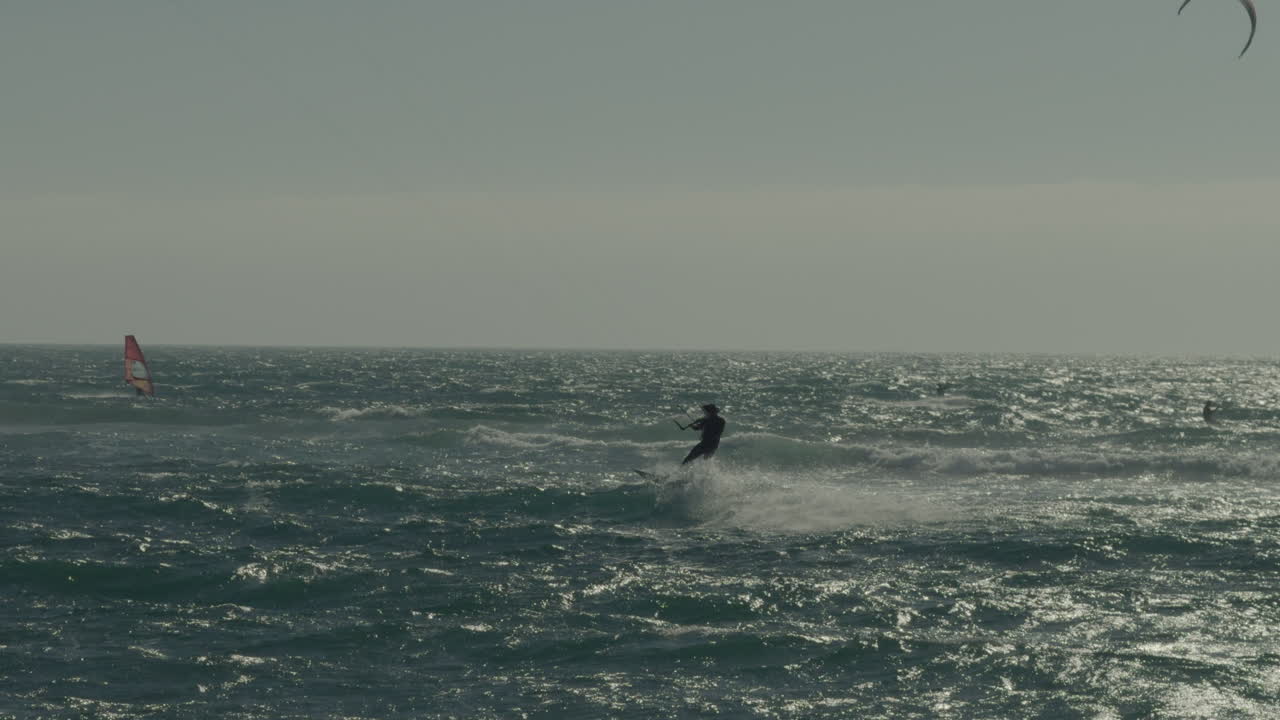 칠레 마탄자스 해안에서 파도에 타고 있는 남성 카이트 서퍼의 실루