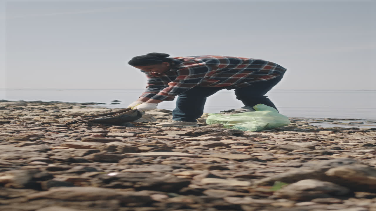 Female Environmental Activist Picking Garbage on Shore