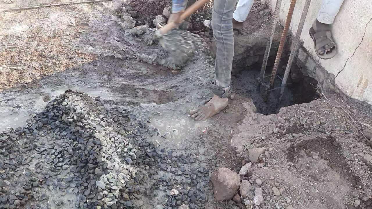 The labor is pouring the cement mix concrete by shovel fawda into the reinforcement column at the construction site in India