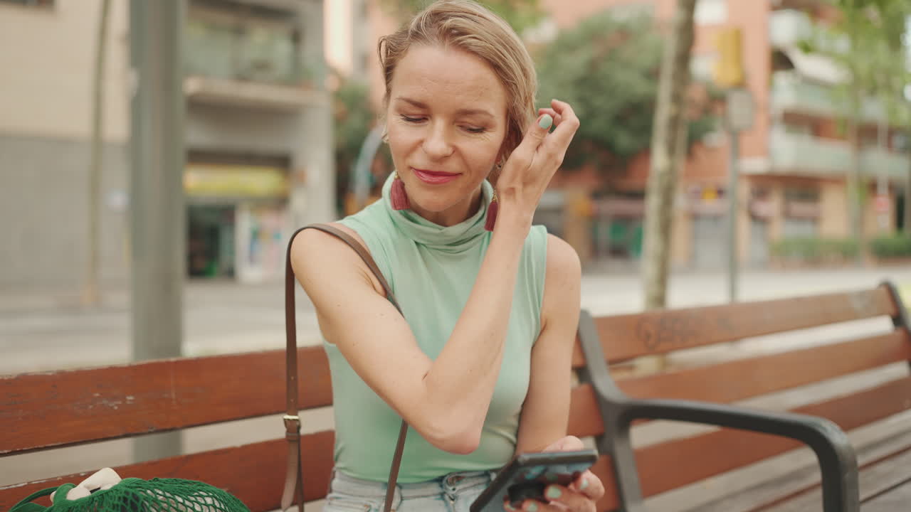 Donna che usa il cellulare su una panchina in città