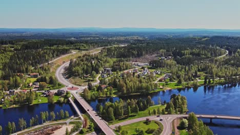 Vista-Aérea-De-Los-Vehículos-Que-Conducen-En-El-Puente-De-La-Carretera-Sobre-El-Río-Vasterdalalven-Con-árboles-Verdes-En-Vansbro,-Dalarna,-Suecia