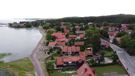 Colorful-red-rooftops-of-Nida-town-in-Lithuania,-aerial-ascending-view