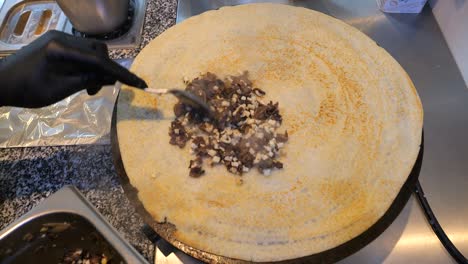 the chef adds the filling onto the spreading pancake