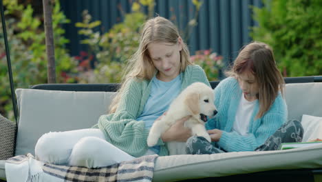 two girls playing with a puppy, sitting on a swing in the backyard of the house