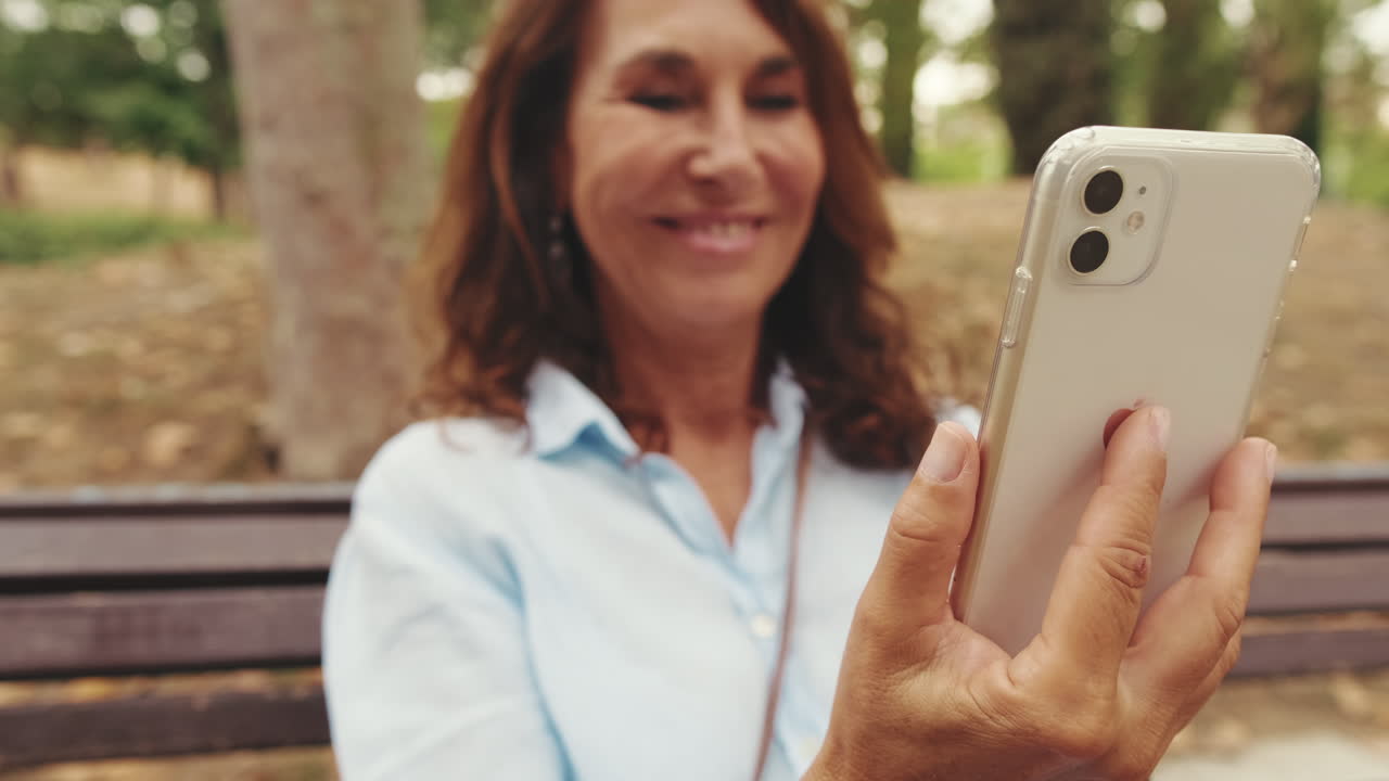 Mulher Madura Sorrindo Enquanto Usa Smartphone em um Parque