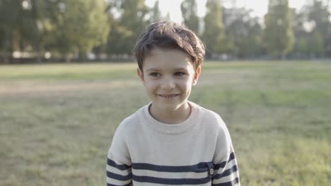 retrato de un lindo niño caucásico saltando mientras sonríe y mira la cámara en el parque