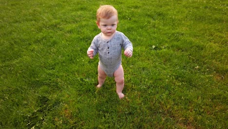 happy toddler takes first steps unassisted without help in grass field