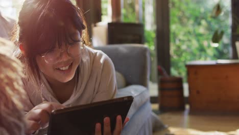 Asiatisches-Mädchen,-Das-Auf-Der-Couch-Liegt-Und-Lächelnd-Ein-Tablet-Benutzt