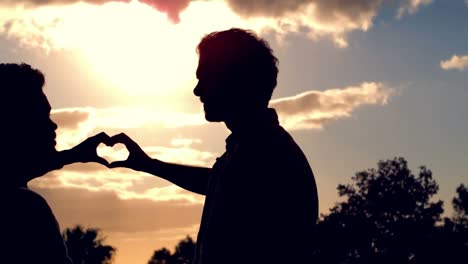 silhouette of homosexual couple doing heart with hands together