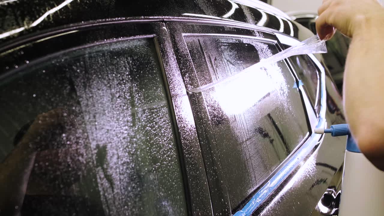 hombre que cubre el coche con cinta de poliuretano de vinilo. películas para el coche. pegatina película protectora en el coche